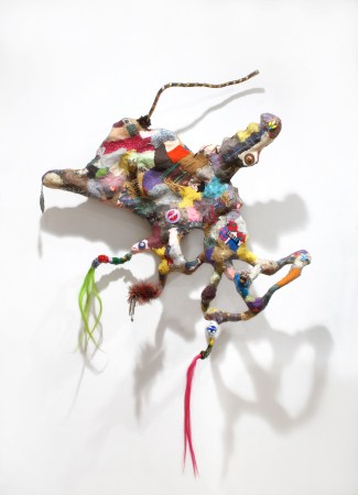 multi-colored patchwork sculpture with two tufts of multi-colored hair