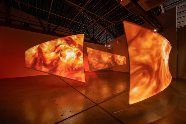 three curved screens with projections of the surface of the sun