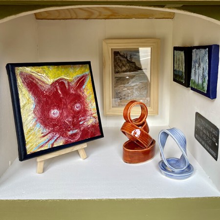 The “Sage Green” gallery at Manzanita's Hoffman Center for the Arts holds a red cat painting by Susan Walsh; Short Sand Beach watercolor by Dorota Haber-Lehigh; watercolors by Tammy Litwinchuk; and ceramic sculptures by Mary Roberts (22 by 17 by 15 inches, spruce with southern yellow pine roof; Plexiglas window).